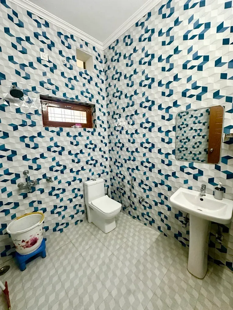 Well-maintained attached washroom with modern sanitary fittings, stylish tiled walls, and essential amenities.